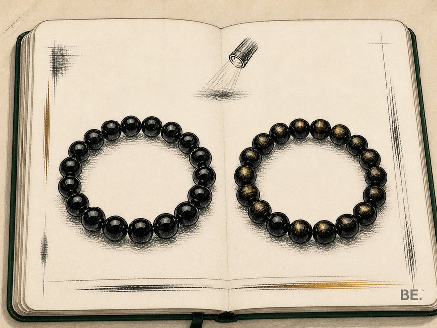 Field-notebook comparison of plain black obsidian and gold sheen obsidian bracelets beneath a directional lamp
