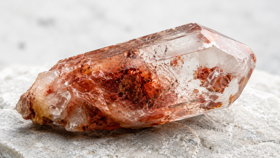 Hematoid quartz crystal with rust-coloured iron oxide needle inclusions inside transparent quartz host