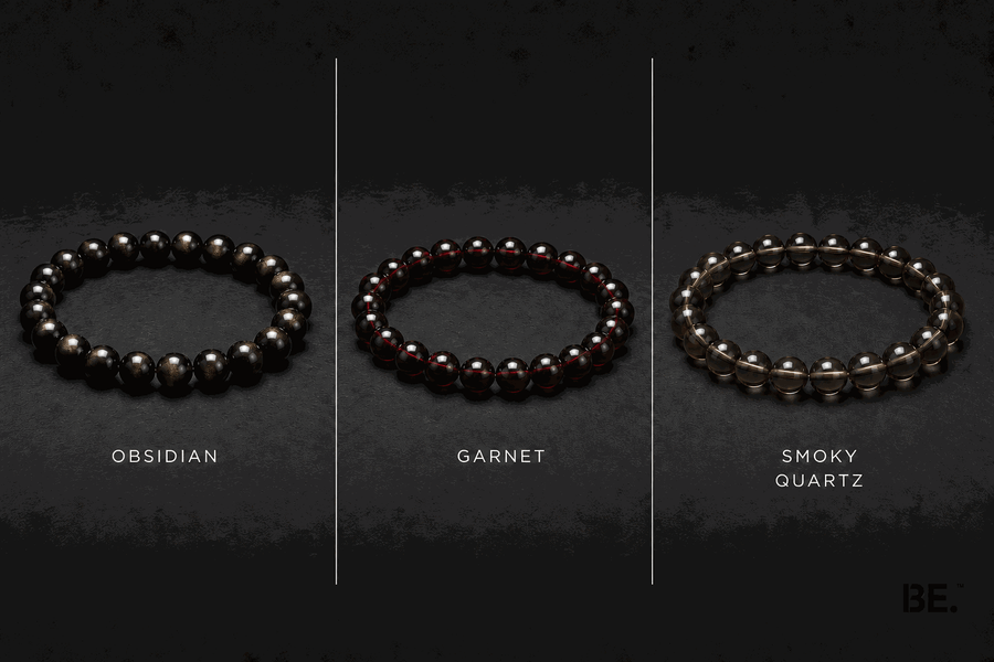 Dark-toned crystal bracelets on a man's wrist — gold sheen obsidian, garnet and smoky quartz strands — BE.