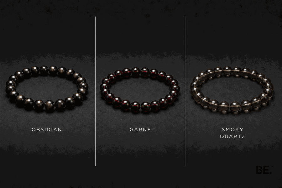 Dark-toned crystal bracelets on a man's wrist — gold sheen obsidian, garnet and smoky quartz strands — BE.