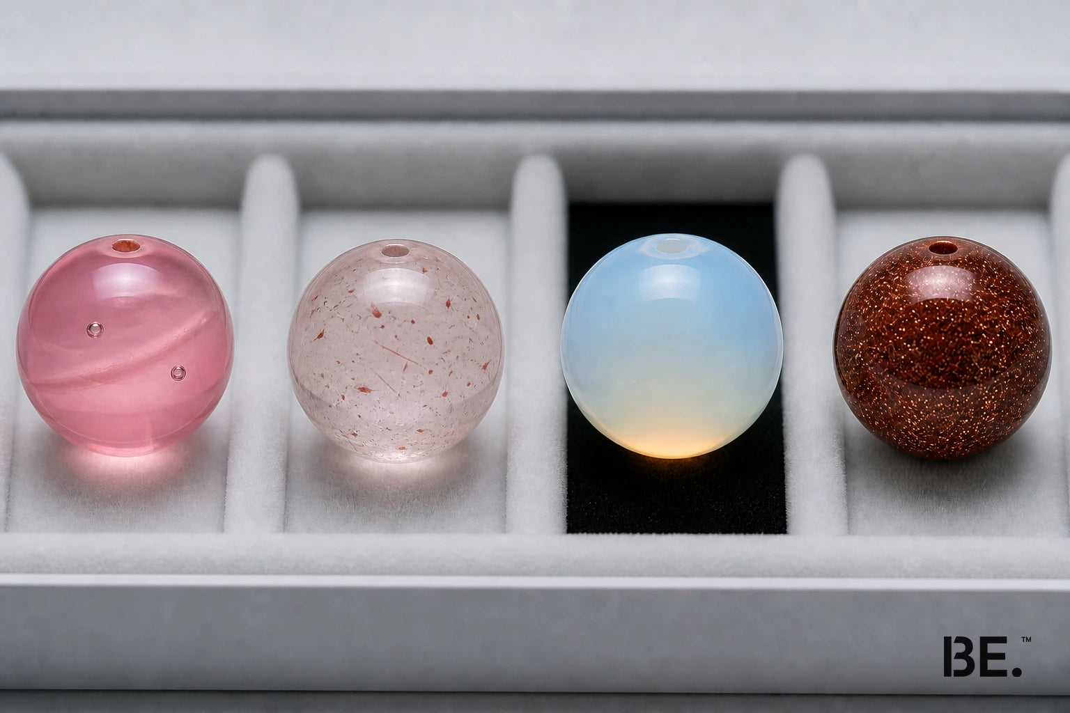 Four pink and luminous bead materials comparing glass, strawberry quartz, opalite-style glass and goldstone — BE.