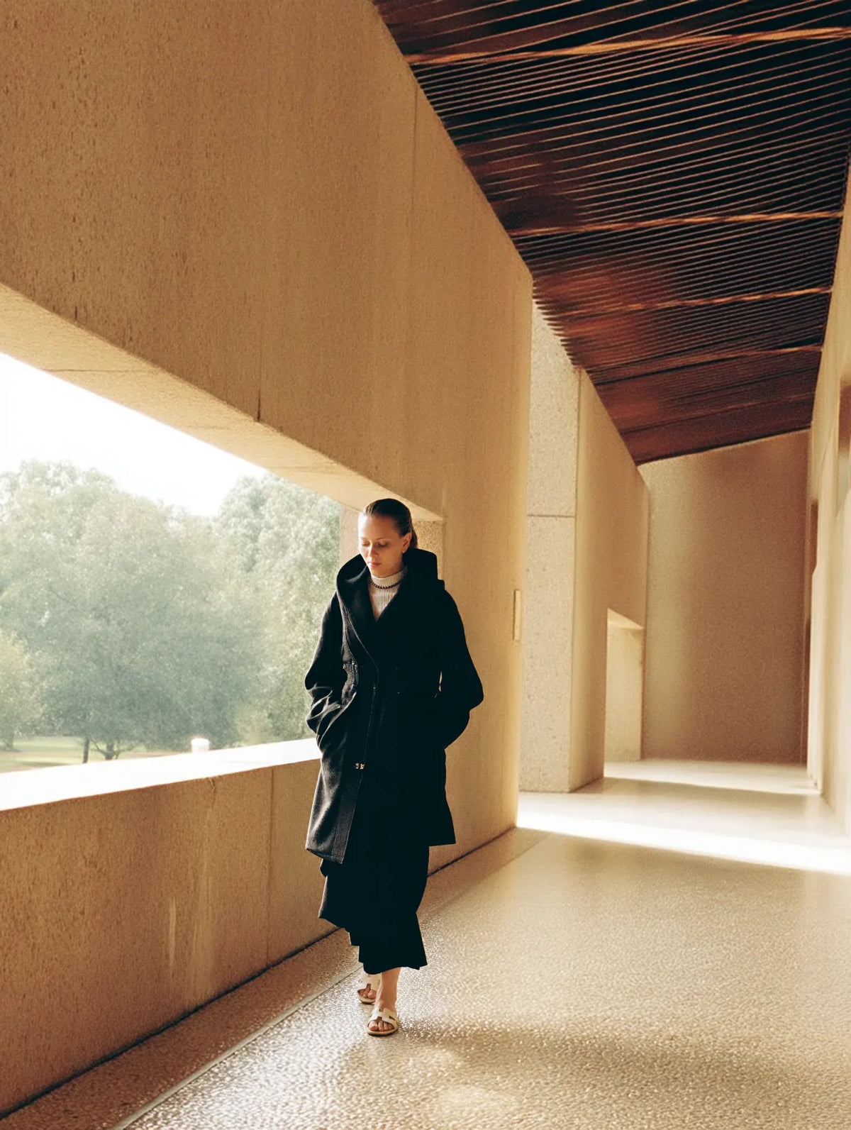 A woman in a quiet dark interior with open negative space