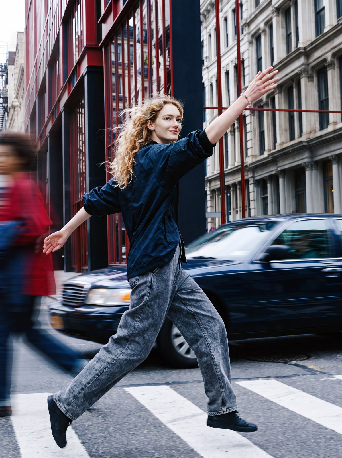 Woman wearing a beaded bracelet moving through a city crosswalk