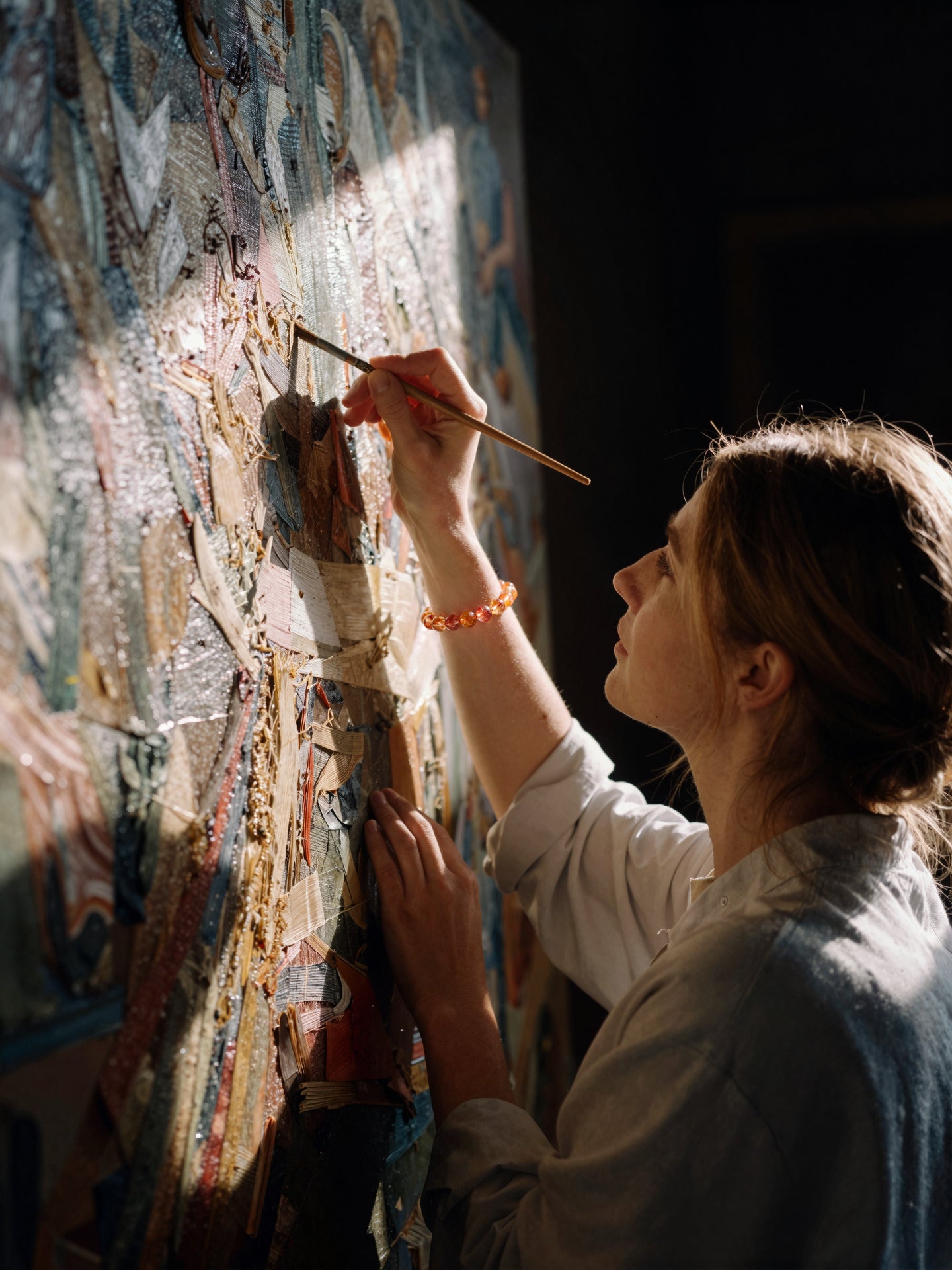 Orange stone bead strand on an artist's wrist as she paints.