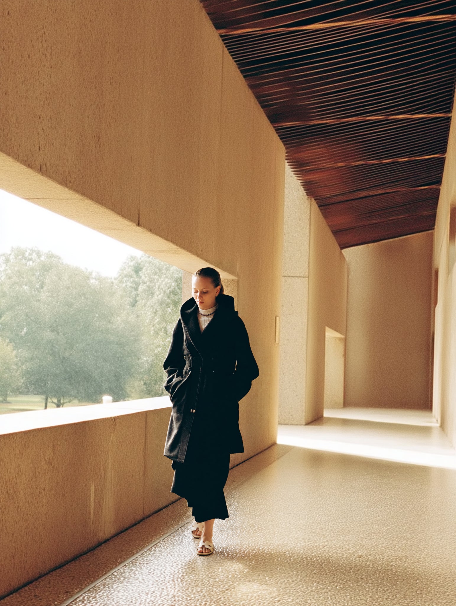 The Void collection: woman in black walking through pale architecture.