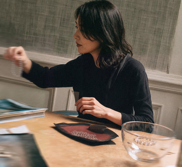 Woman sorting clear quartz beads at a studio worktable