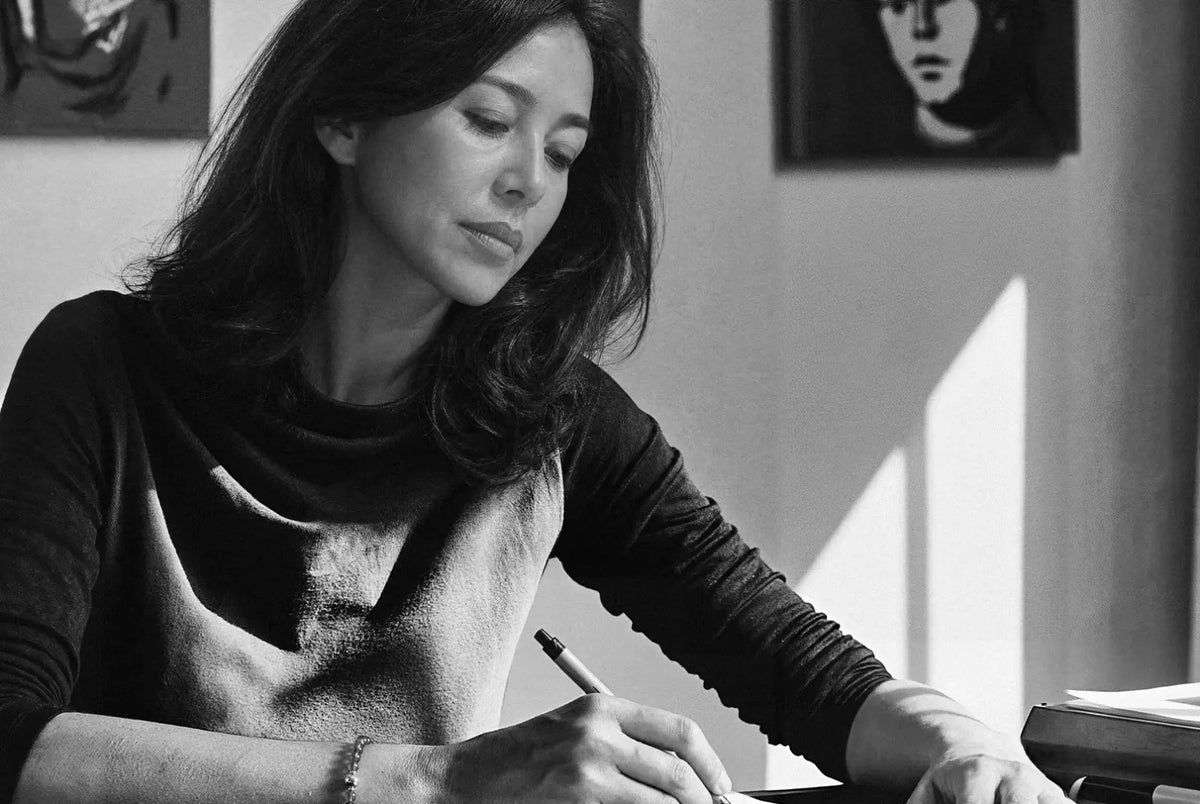 Woman drawing in a notebook at a desk.