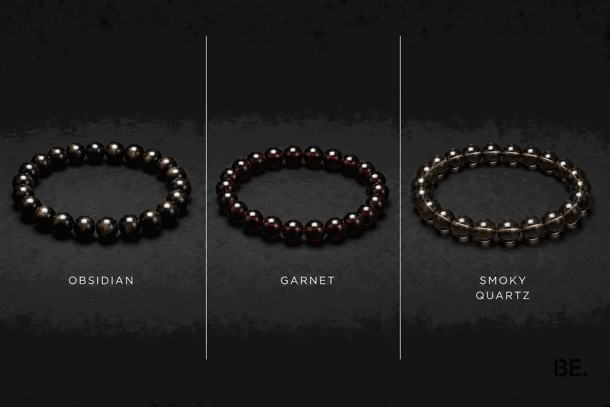 Dark-toned crystal bracelets on a man's wrist — gold sheen obsidian, garnet and smoky quartz strands — BE.