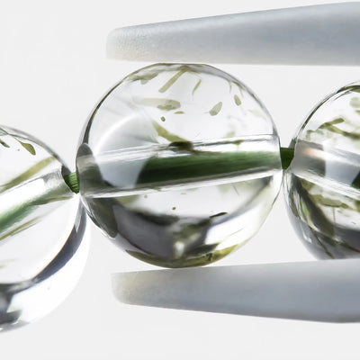 Green Rutilated Quartz Bracelet close-up — fine green mineral needles suspended in clear quartz, angled view, BE.