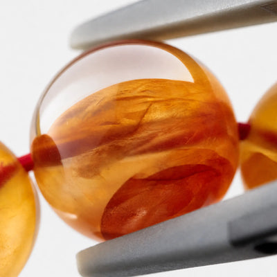 Koi Phantom Quartz Bracelet close-up — iron-oxide red clouds in quartz, angled view, BE.